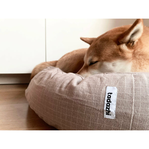 organic round dog cushion with a shiba inu resting on it